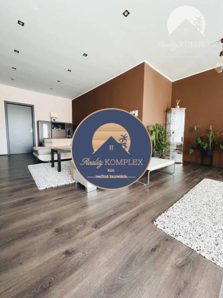 Vám ponuka na predaj útulný 3-izbový rodinný d - Obývacia izba v rodinnom dome s podlahou s dreveným dekorom a hnedými stenami.