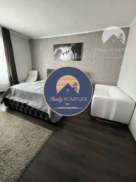 Vám ponuka na predaj útulný 3-izbový rodinný d - Spálňa v rodinnom dome s podlahou s dreveným dekorom a béžovým kobercom.