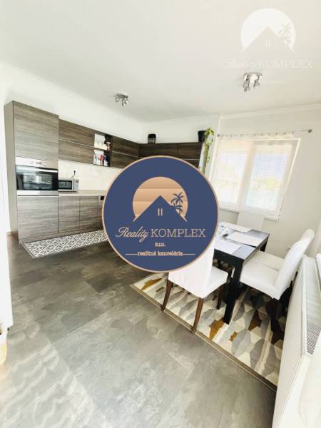 Vám ponuka na predaj útulný 3-izbový rodinný d - Kuchyňa v rodinnom dome s podlahou s dreveným dekorom a jedálenským stolom.