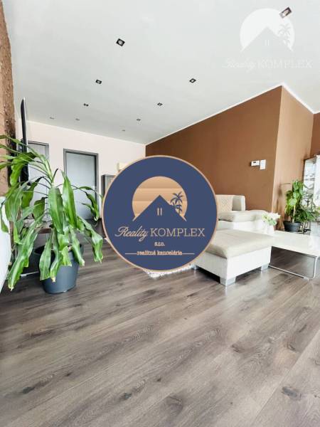 Vám ponuka na predaj útulný 3-izbový rodinný d - Obývacia izba v rodinnom dome s podlahou s dreveným dekorom a zelenými rastlinami.