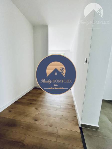 Vám ponúka na predaj moderný 4-izbový bungalov - Chodba v rodinnom dome s podlahou s dreveným dekorom a bielymi stenami.