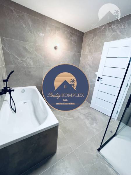 Vám ponúka na predaj moderný 4-izbový bungalov - Kúpeľňa s vaňou a sprchovacím kútom v rodinnom dome, dlažba s jemným vzorom.