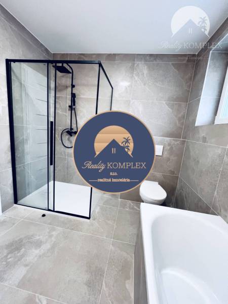 Vám ponúka na predaj moderný 4-izbový bungalov - Kúpeľňa rodinného domu s veľkoformátovými dlaždicami, sprchovacím kútom a vaňou.