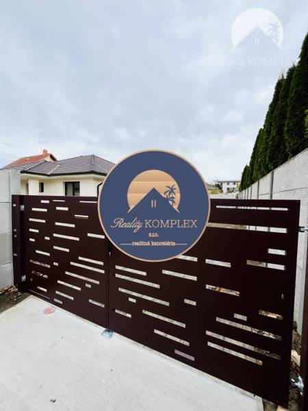 Vám ponúka na predaj moderný 4-izbový bungalov - Brána pred rodinným domom v Topoľníkoch s dizajnom horizontálnych otvorov.