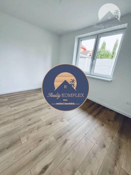 Vám ponúka na predaj moderný 4-izbový bungalov - Biela miestnosť s podlahou s dreveným dekorom v rodinnom dome.