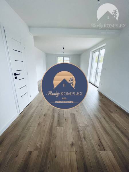 Vám ponúka na predaj moderný 4-izbový bungalov - Interiér rodinného domu s bielymi stenami a podlahou s dreveným dekorom.