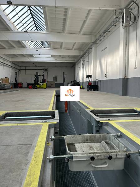 Autoservis s výbavou pre vozidlá v uzavretom priemyselnom areáli - HC - Priemyselný priestor s nabíjacou stanicou, technikou a svetlíkom v budove.