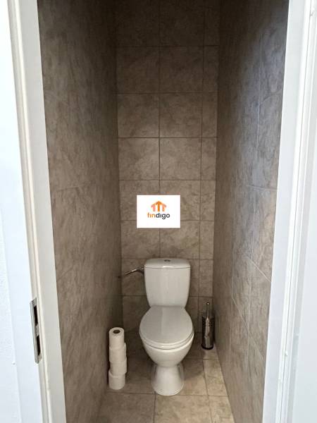 Autoservis s výbavou pre vozidlá v uzavretom priemyselnom areáli - HC - Toaleta v budove s dlažbou béžovej farby a toaletným papierom.