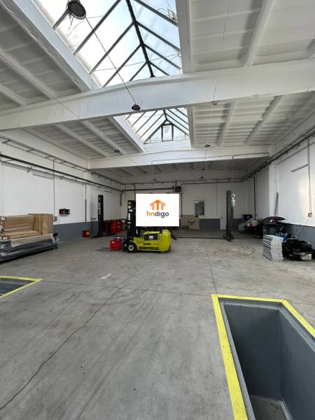 Autoservis s výbavou pre vozidlá v uzavretom priemyselnom areáli - HC - Priemyselný interiér budovy s presvetlenou strechou a žltým vysokozdvižným vozíkom.