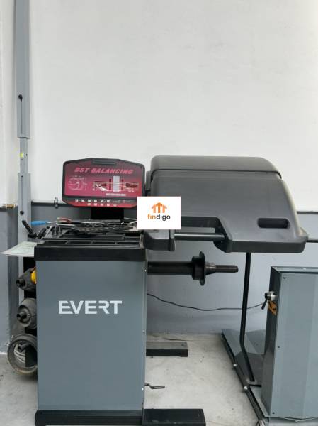 Autoservis s výbavou pre vozidlá v uzavretom priemyselnom areáli - HC - Vyvažovací stroj EVERT v budove autoservisu, vhodný na údržbu vozidiel.