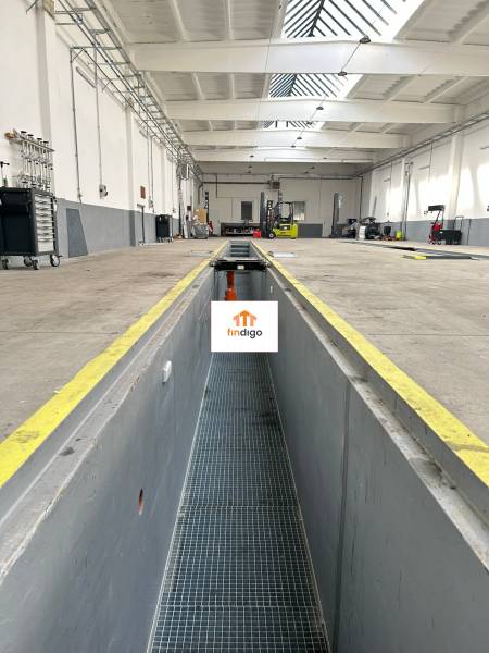 Autoservis s výbavou pre vozidlá v uzavretom priemyselnom areáli - HC - Interiér budovy s vysokým stropom, servisnou jamou, náradím a vybavením.