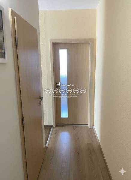 Exkluzívne v našej RK 3 izbový byt po rekonštrukcii s dvomi loggiami - Chodba v 3-izbovom byte s podlahou s dreveným dekorom a svetlými dverami.