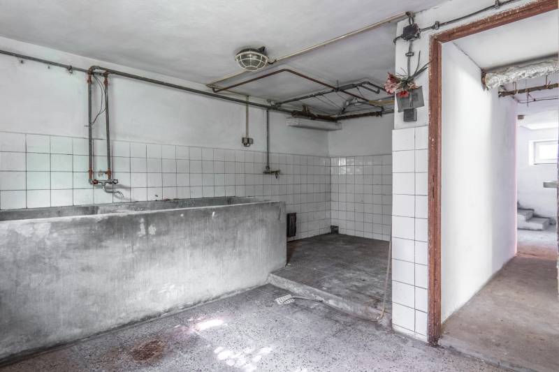 I Na predaj dvojposchodový 5i rodinný dom pri Žiline - Suterén rodinného domu s šedým umývadlom, bielymi obkladačkami a betónovou podlahou.