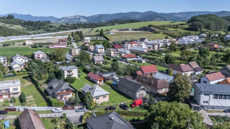 I Na predaj dvojposchodový 5i rodinný dom pri Žiline - Letecký pohľad na rodinné domy v Lietavskej Lúčke na M. Chmeliara, obklopené zeleňou a horami.