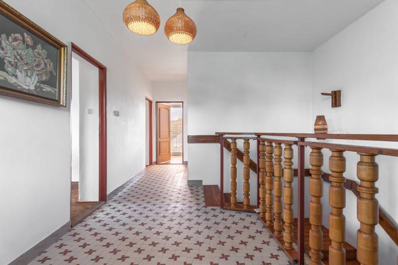 I Na predaj dvojposchodový 5i rodinný dom pri Žiline - Chodba v rodinnom dome s keramickou dlažbou, dreveným zábradlím a obrazom na stene.