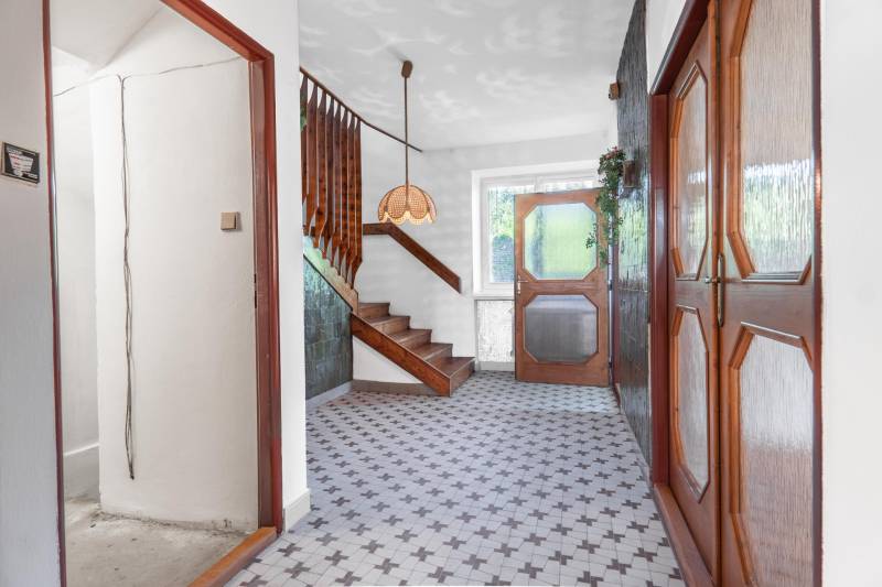 I Na predaj dvojposchodový 5i rodinný dom pri Žiline - Chodba v rodinnom dome s dlažbou, drevenými dverami a schodiskom.