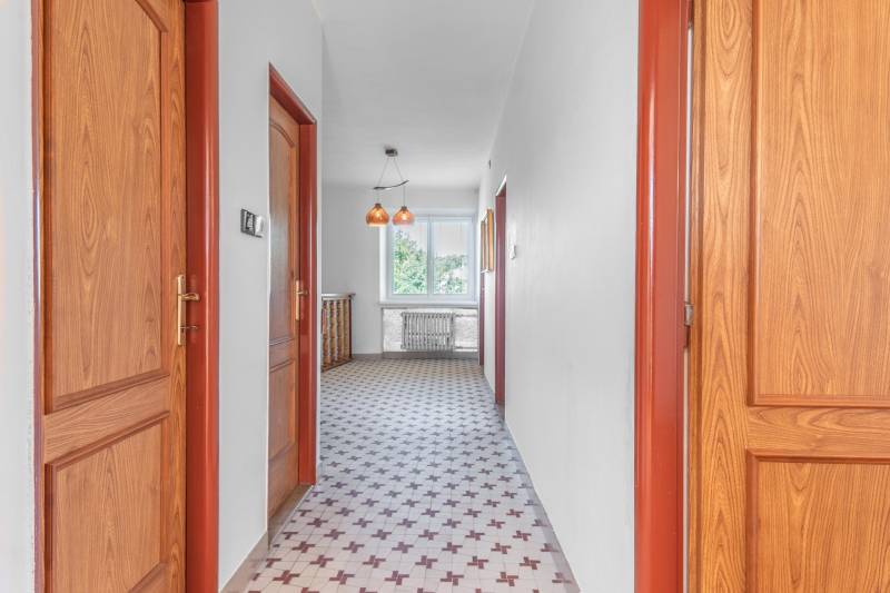 I Na predaj dvojposchodový 5i rodinný dom pri Žiline - Chodba v rodinnom dome s dlažbou, drevenými dverami a visiacimi lampami.