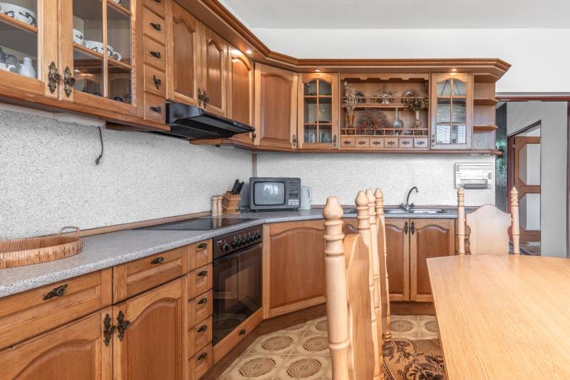 I Na predaj dvojposchodový 5i rodinný dom pri Žiline - Kuchyňa s dreveným dekorom a rustikálnymi skrinkami v rodinnom dome.