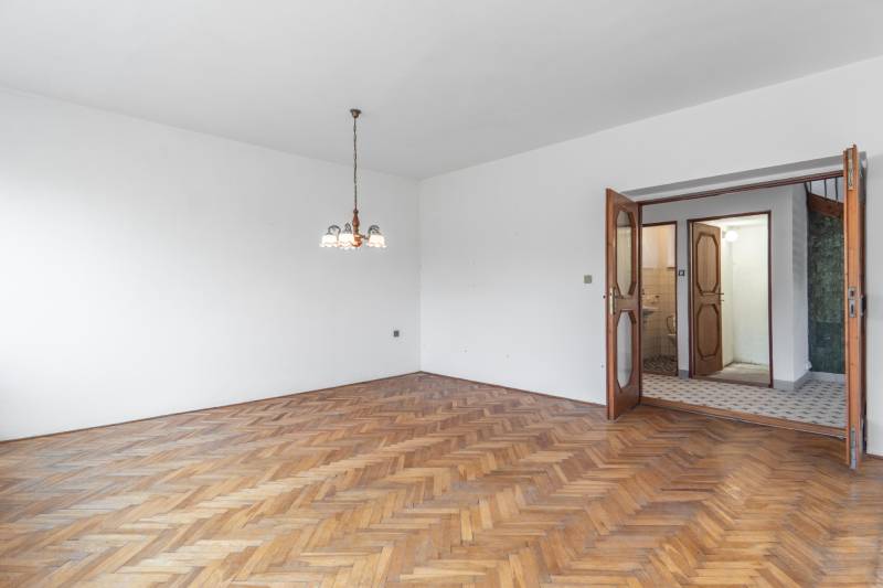 I Na predaj dvojposchodový 5i rodinný dom pri Žiline - Interiér rodinného domu s podlahou s dreveným dekorom a závesným osvetlením.