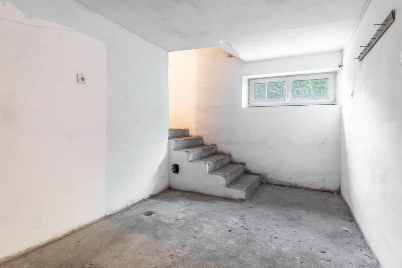 I Na predaj dvojposchodový 5i rodinný dom pri Žiline - Betónové schody vedú do pivnice v rodinnom dome, s malým oknom a bielymi stenami.