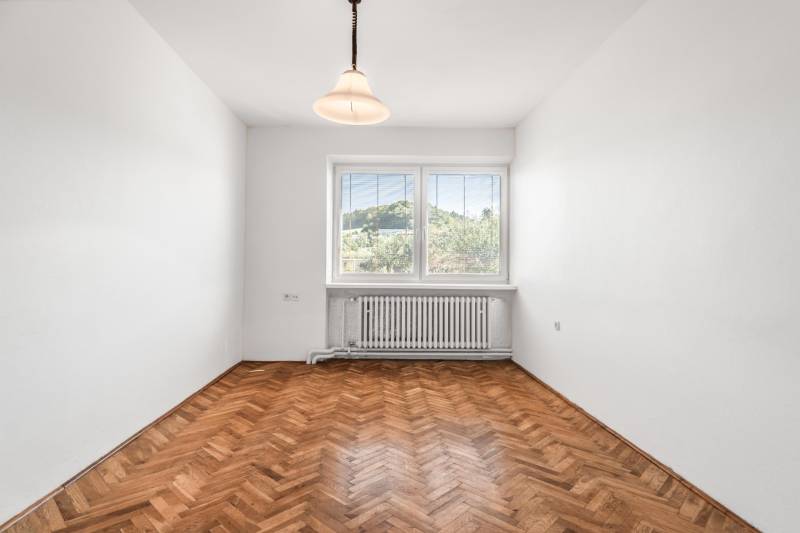 I Na predaj dvojposchodový 5i rodinný dom pri Žiline - Izba v rodinnom dome s jednoduchým osvetlením a podlahou s dreveným dekorom.