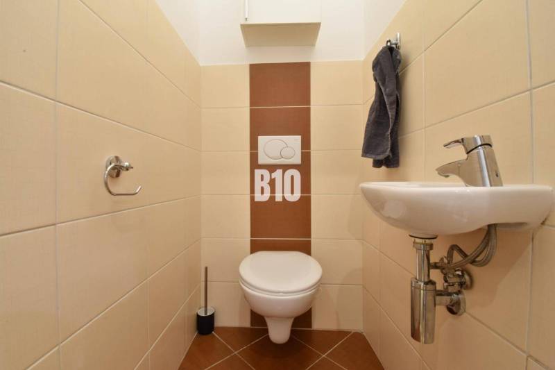 Veľkometrážny 3 izbový byt s garážou - Toaleta s umývadlom v 3-izbovom byte, obložená svetlými obkladmi.