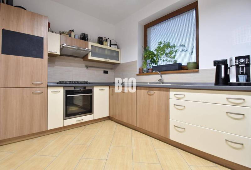 Veľkometrážny 3 izbový byt s garážou - Kuchyňa v 3-izbovom byte s rohovou linkou a podlahou s dreveným dekorom.