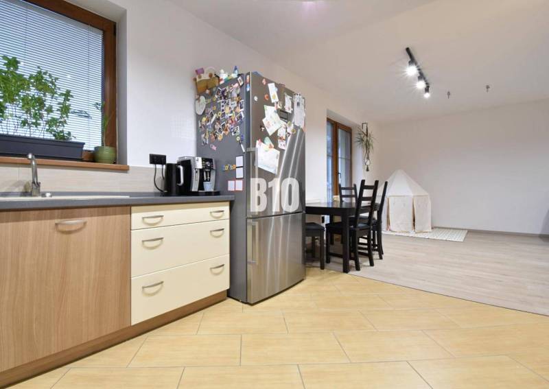 Veľkometrážny 3 izbový byt s garážou - Kuchyňa v 3-izbovom byte s dreveným dekorom podlahy a jedálenským stolom.