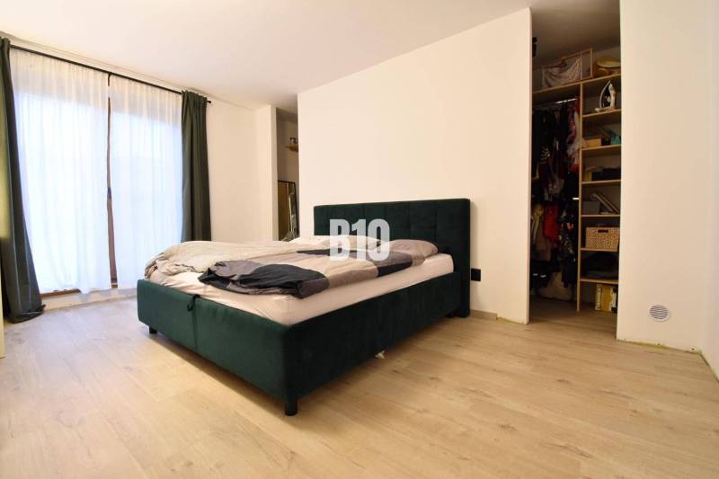 Veľkometrážny 3 izbový byt s garážou - Spálňa s posteľou, podlahou s dreveným dekorom a šatníkom v 3-izbovom byte.