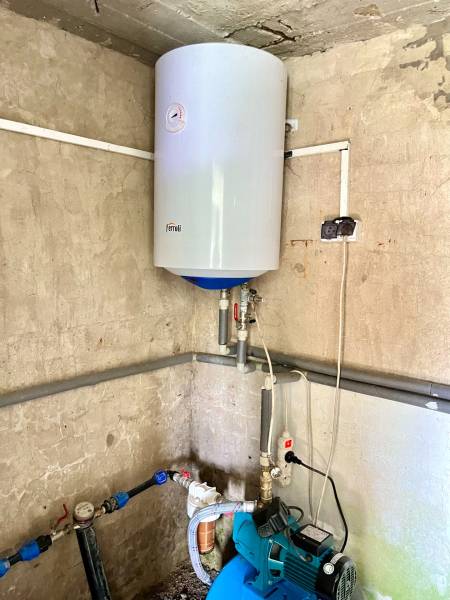 Rekreačná chata – Banská Štiavnica, časť Štefultov - Kotol na stene a čerpadlo v rohu v rodinnom dome.