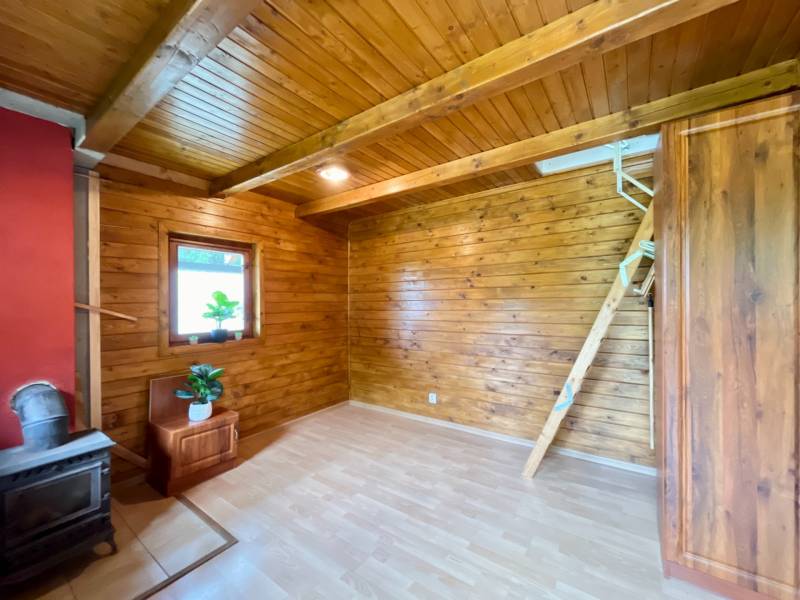 Rekreačná chata – Banská Štiavnica, časť Štefultov - Interiér chaty s drevenými prvkami, pieckou a podlahou s dreveným dekorom.