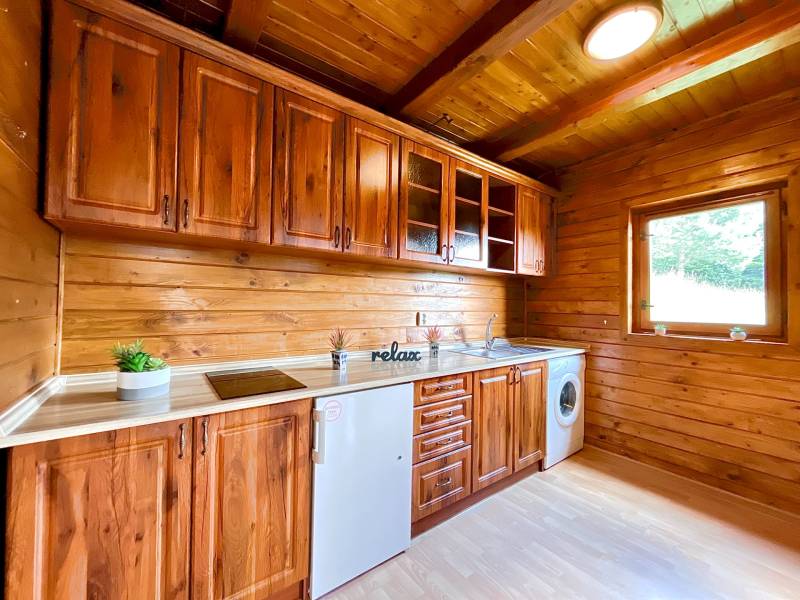 Rekreačná chata – Banská Štiavnica, časť Štefultov - Drevená kuchyňa v rodinnom dome s drevenými skrinkami a výhľadom z okna.