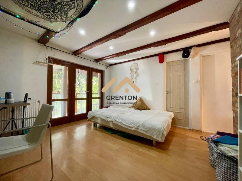 4 izbová celoročná chata v Kučišdorfskej doline na predaj - Interiér chaty s posteľou, stoličkou a podlahou s dreveným dekorom.