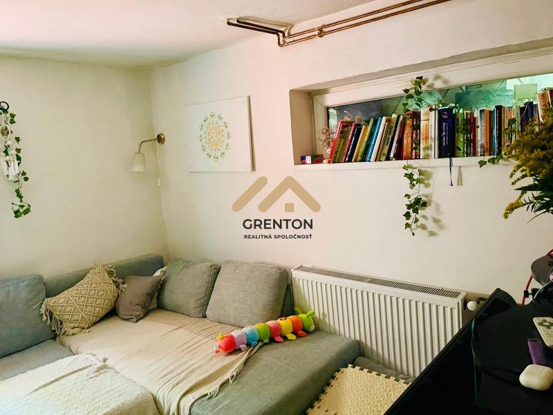 4 izbová celoročná chata v Kučišdorfskej doline na predaj - Pohodlný gauč v chate s vankúšmi, knihami a dekoráciou na stene.