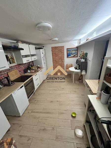 4 izbová celoročná chata v Kučišdorfskej doline na predaj - Kuchyňa v chate s podlahou s dreveným dekorom, svetlými skrinkami a jedálenským stolom.