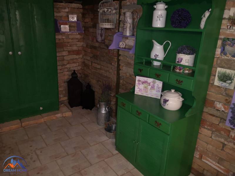 MH283 – Na predaj krásny rodinný dom vo vidieckom štýle - Rodinný dom s tehlovou stenou, zeleným nábytkom a dekoráciami s levanduľovým motívom.