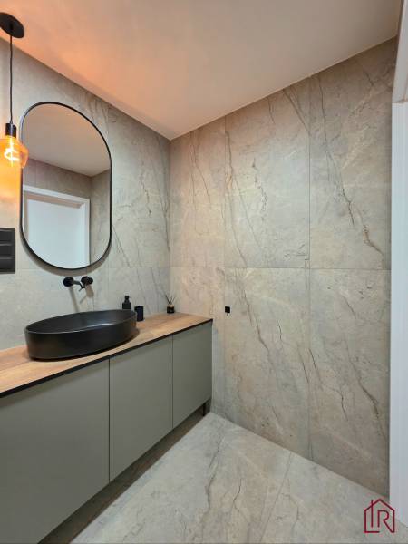 REZERVOVANÝ - Moderný 3-izbový byt po rekonštrukcii na Terase, Košice - Kúpeľňa v 3-izbovom byte s umývadlom na drevenom dekore a čiernym svietidlom.