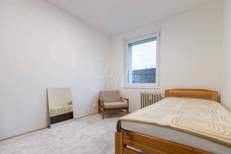 Slnečný 3-izbový byt, Kramáre - Izba v 3-izbovom byte s kreslom, posteľou a oknom.