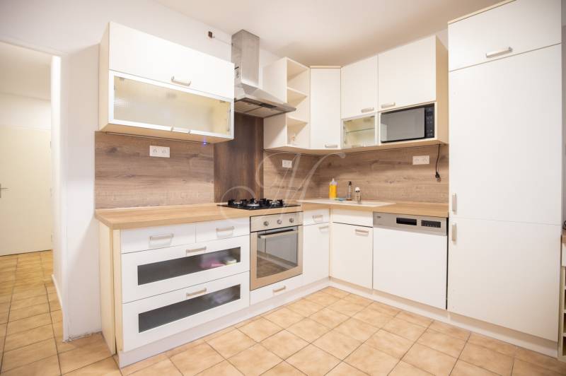 Slnečný 3-izbový byt, Kramáre - Kuchyňa v 3-izbovom byte s bielymi skrinkami a podlahou s dreveným dekorom.