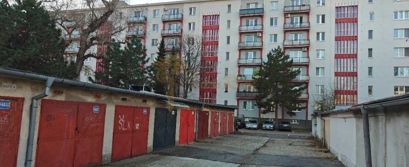 Garáž, Haburská ul., Ružinov pri Štrkovci - Garáže na Haburskej ulici, Bratislava - Ružinov, pred bytovým domom s červenými detailmi.