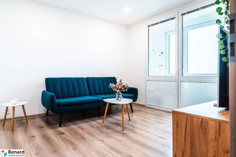 Útulný 2-izbový byt na prenájom - Obývačka v 2-izbovom byte so sedačkou, podlahou s dreveným dekorom a konferenčným stolíkom.