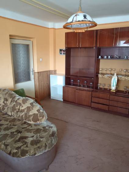 Na predaj rodinný dom Kosihovce - Obývačka v rodinnom dome s pohovkou a vitrínou s pohármi.