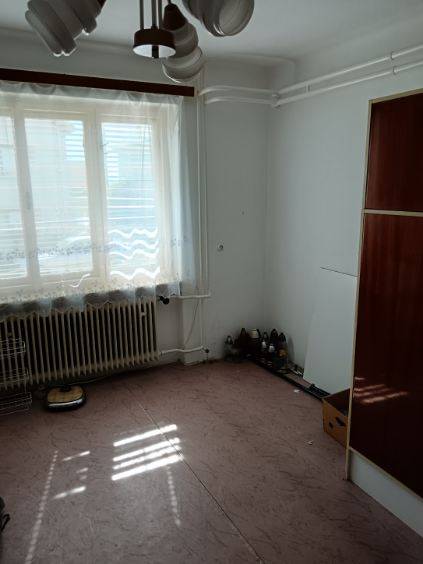 Na predaj rodinný dom Kosihovce - Izba v rodinnom dome s veľkým oknom a radiátorom, prázdna podlaha.