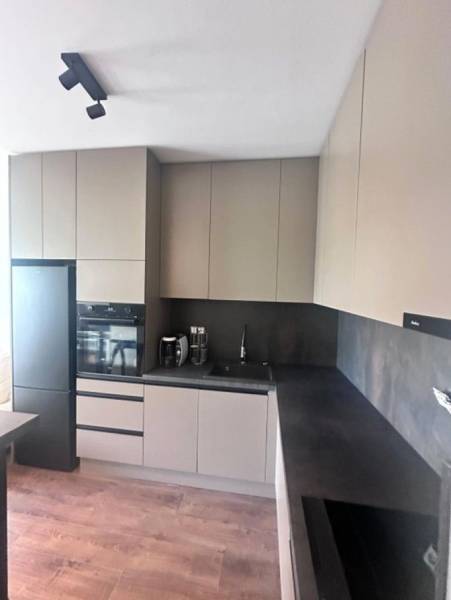 Na prenájom 2iz. byt s predzáhradkou  - Kuchyňa v 2-izbovom byte s tmavou pracovnou doskou a podlahou s dreveným dekorom.