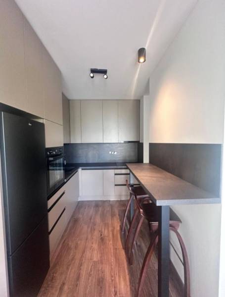 Na prenájom 2iz. byt s predzáhradkou  - Kuchyňa s barovým pultom a podlahou s dreveným dekorom v 2-izbovom byte.