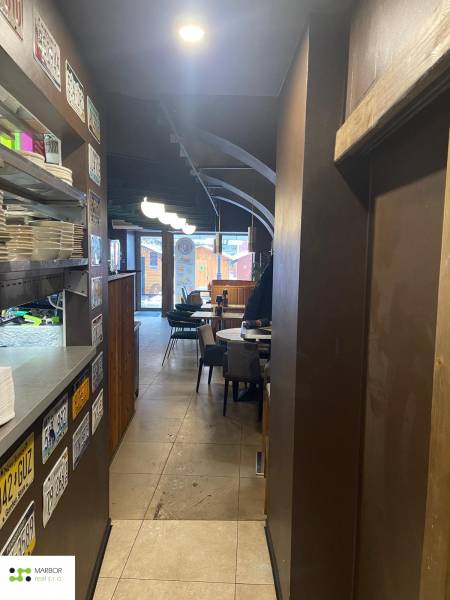 Reštaurácia na predaj v centre Košíc na Hlavnej 74 - Interiér gastro priestorov s taniermi na polici, tabule, stoly a stoličky.