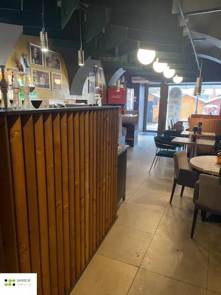 Reštaurácia na predaj v centre Košíc na Hlavnej 74 - Interiér gastro priestorov s dreveným barom a stolmi. Vidieť aj dekoratívne osvetlenie.