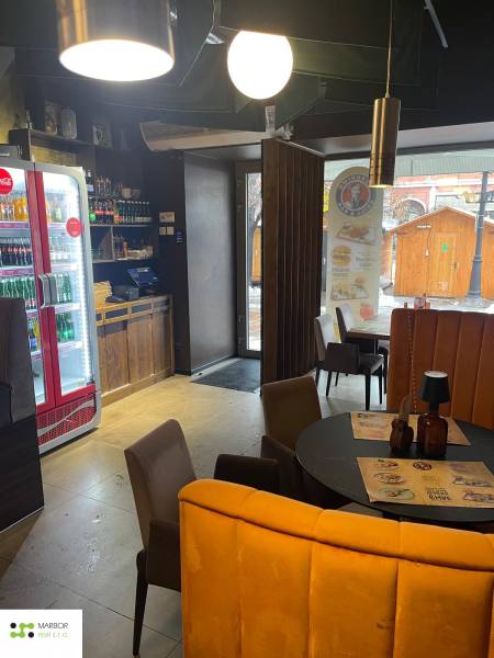 Reštaurácia na predaj v centre Košíc na Hlavnej 74 - Interiér gastro priestorov s kruhovým stolom, stoličkami a osvetlením.