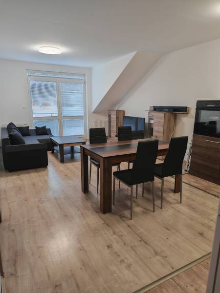 Prenájom 3-izbový byt v Malackách - Obývačka v 3-izbovom byte s podlahou s dreveným dekorom a jedálenským stolom.