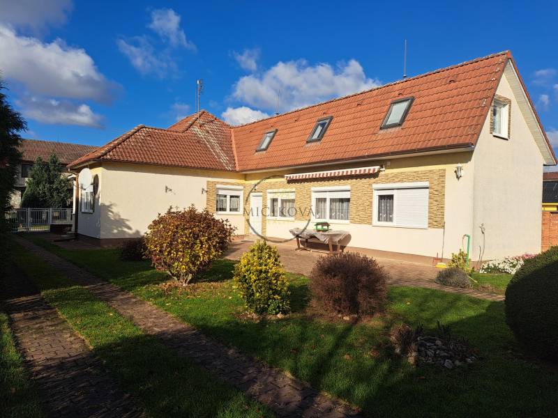 REZERVOVANÉ! Predáme 4-izb. rodinný dom, pozemok 1414 m2, Vráble - Rodinný dom na Bernolákovej ulici vo Vrábľoch, obklopený zelenou záhradou a modrou oblohou.